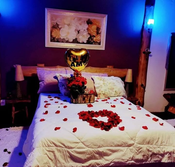 Chalé Roxo — hidromassagem em paredes de pedra com iluminação em tons de roxo e vermelho
